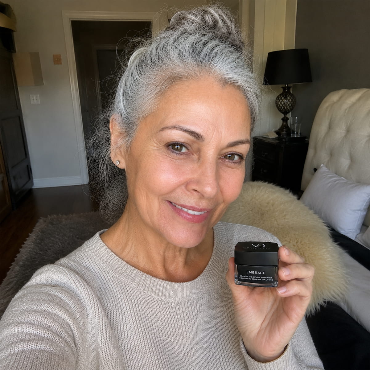 Mature woman holding Vorabelle Embrace Collagen and Oatmeal Moisturizer in a real customer review photo at home.